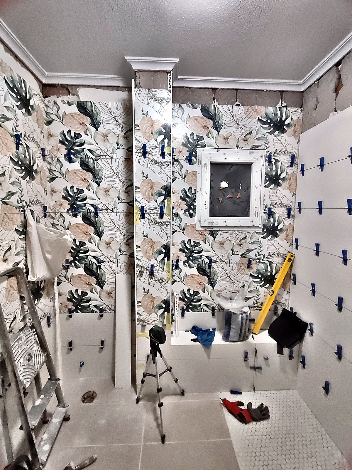 Alicatado de baño con azulejo floral y niveladores durante la obra