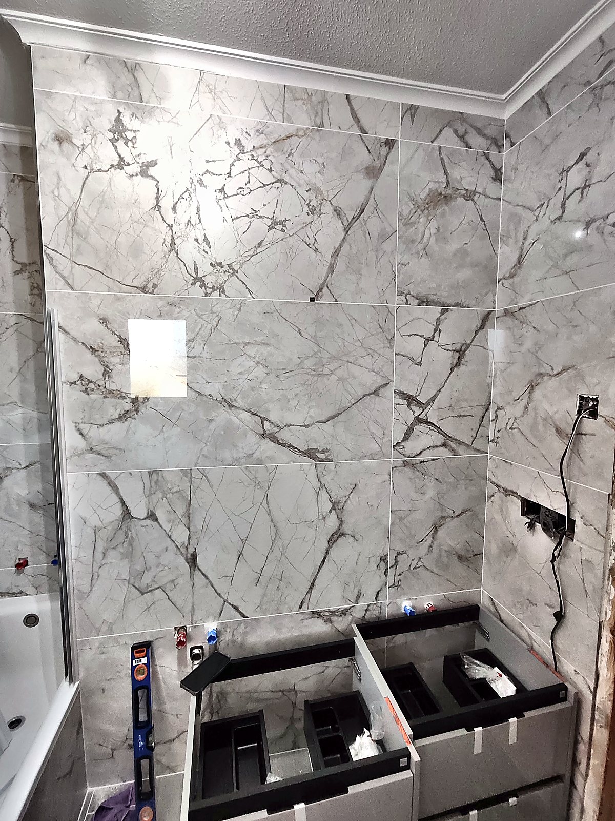 Baño reformado con porcelánico efecto mármol en paredes