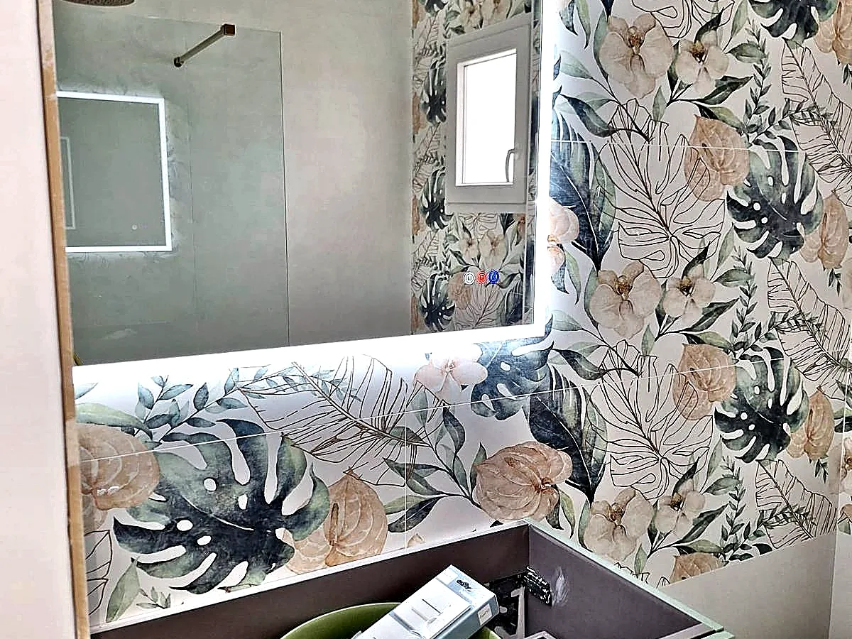 Baño reformado con azulejo decorativo floral y espejo LED