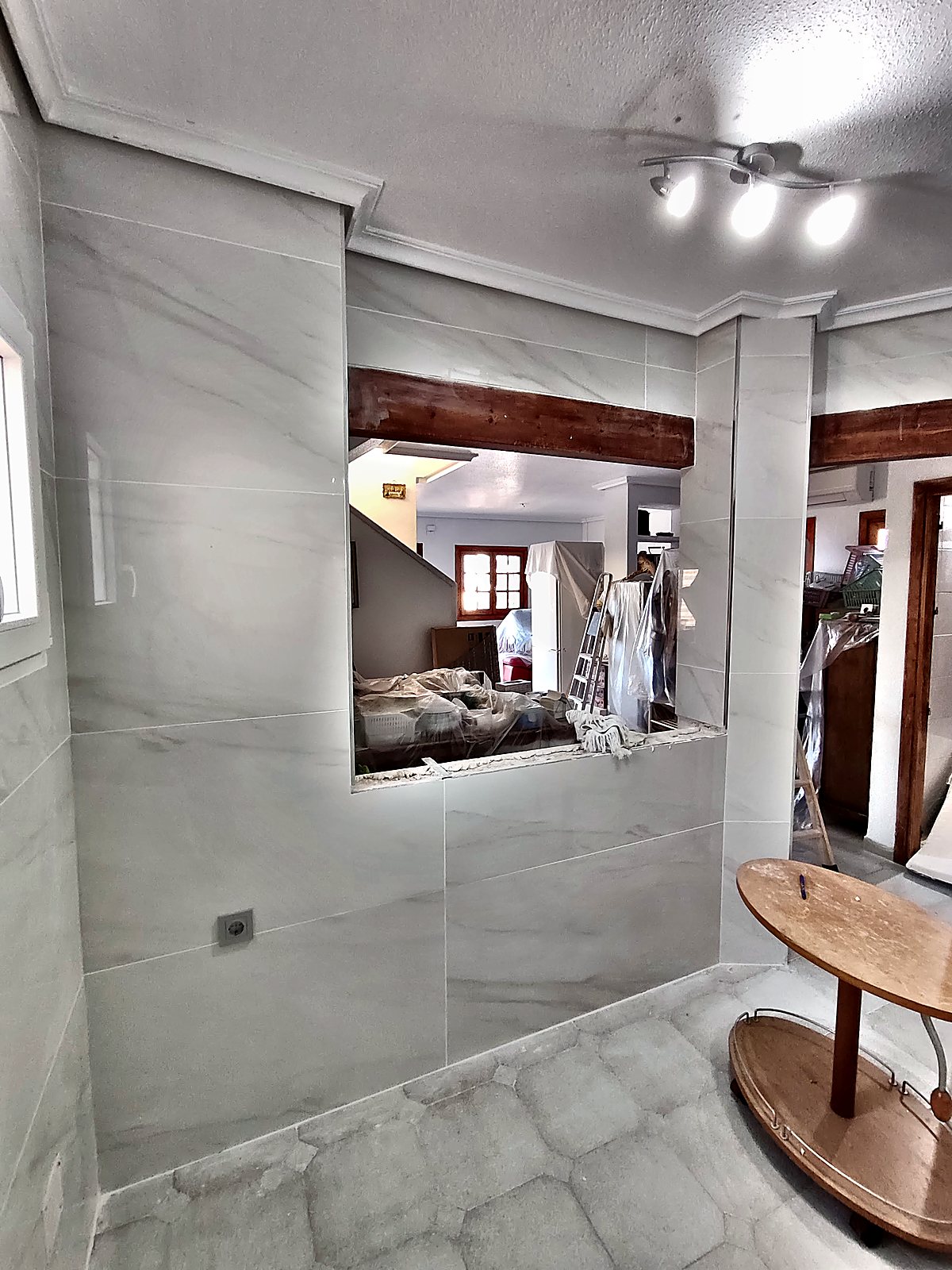 Cocina abierta con pasaplatos y paredes de porcelánico
