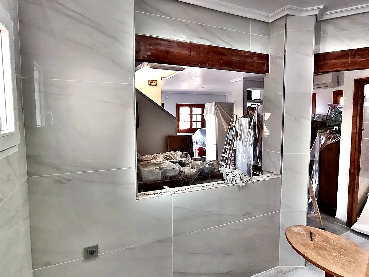 Cocina abierta con pasaplatos y paredes de porcelánico