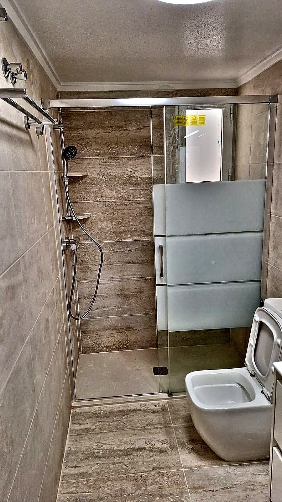 Ducha alargada con mampara fija en un baño reformado en Murcia