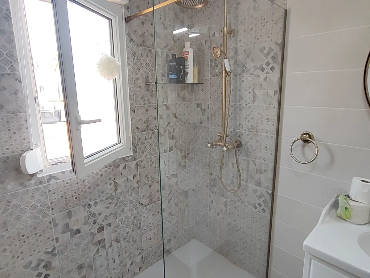 Ducha de obra con grifería dorada y mampara fija