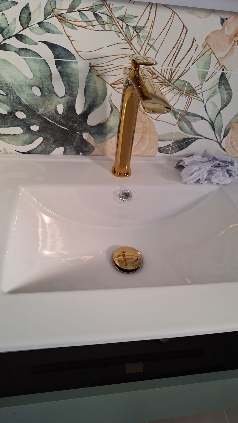 Lavabo con grifo dorado y azulejo floral en un baño reformado en Murcia