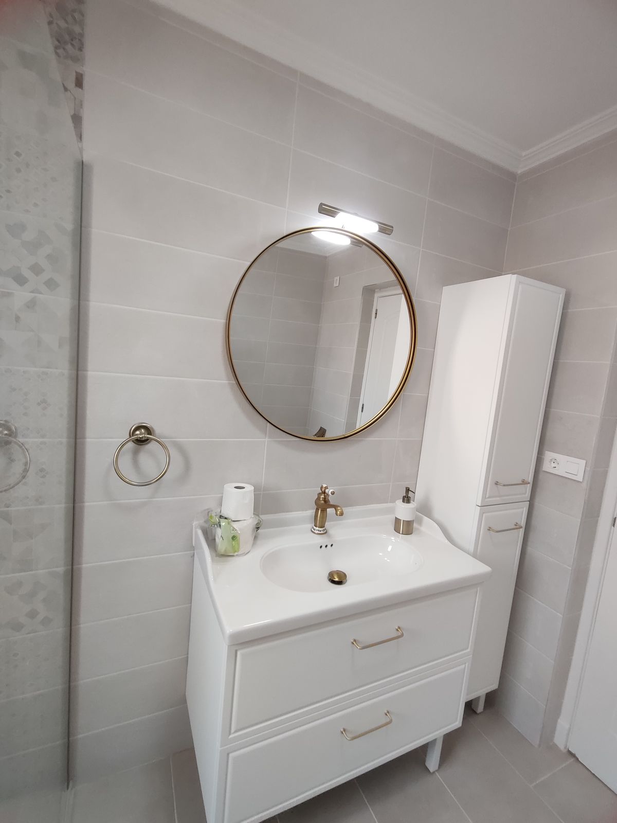 Baño reformado con espejo redondo y mueble columna en Murcia