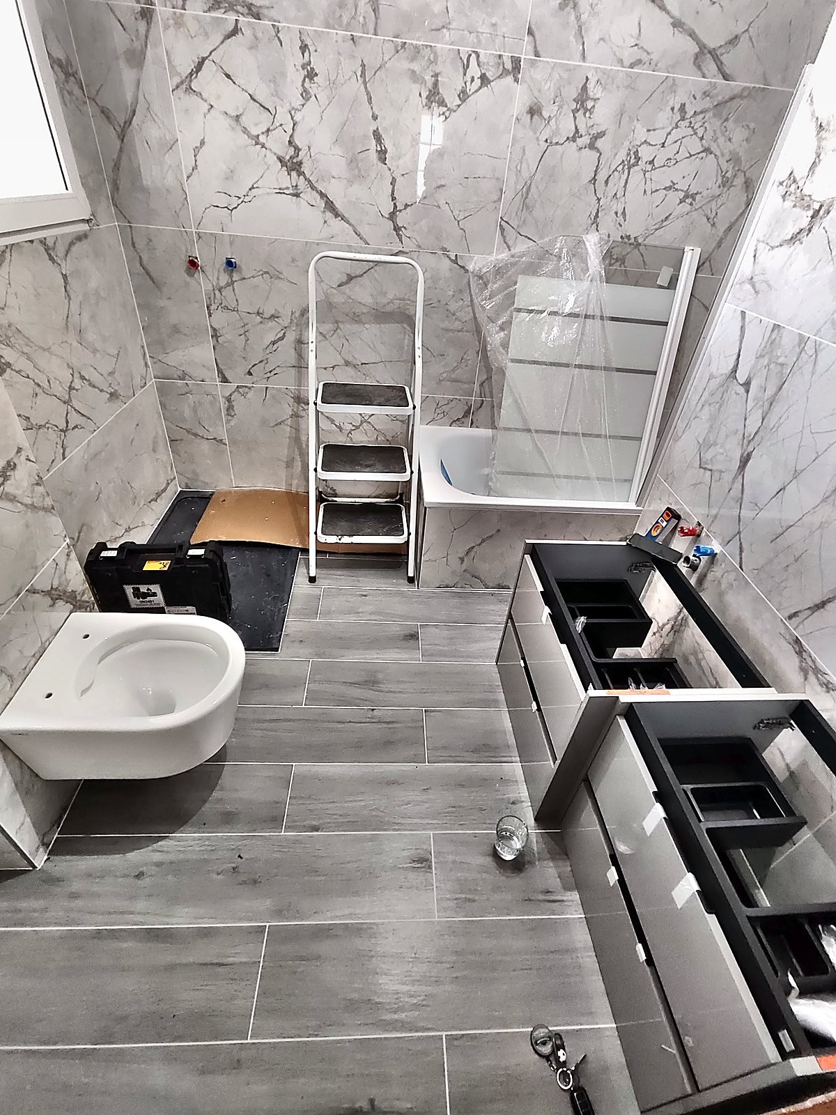 Baño con porcelánico efecto mármol y suelo imitación madera