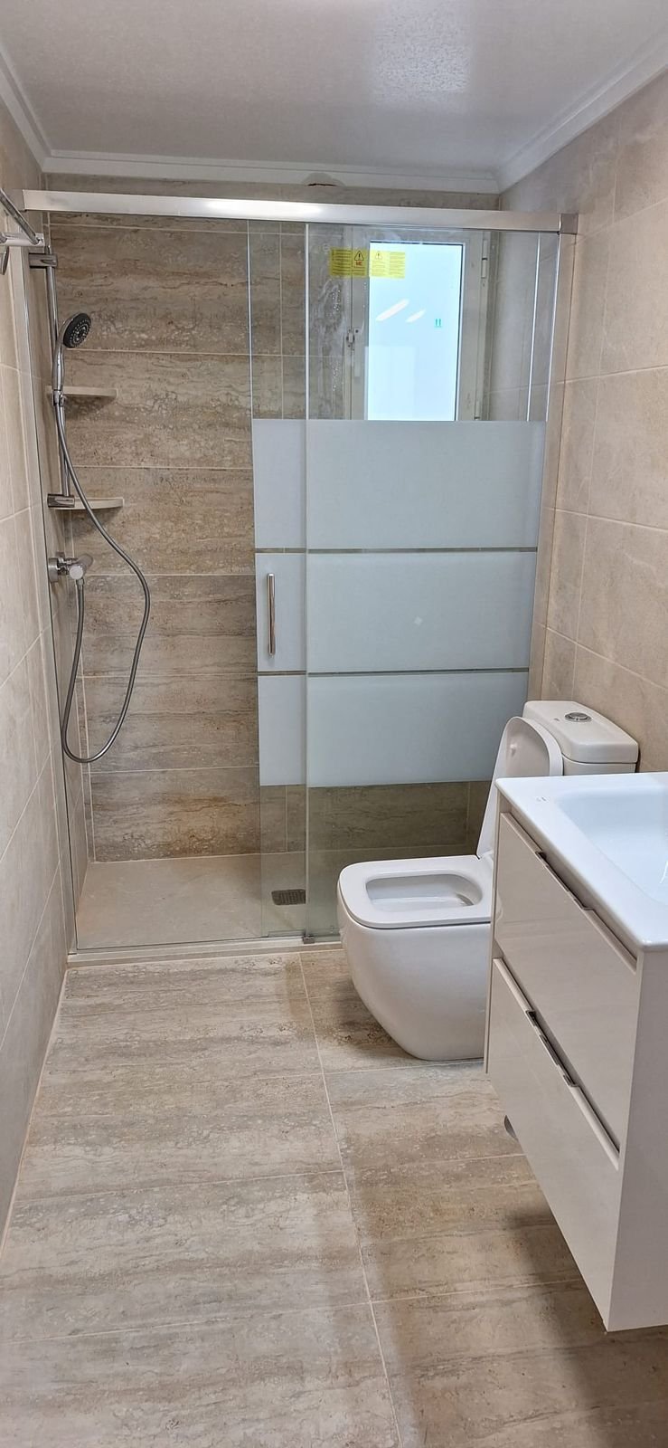 Ducha alargada con mampara corredera en el hueco de la bañera